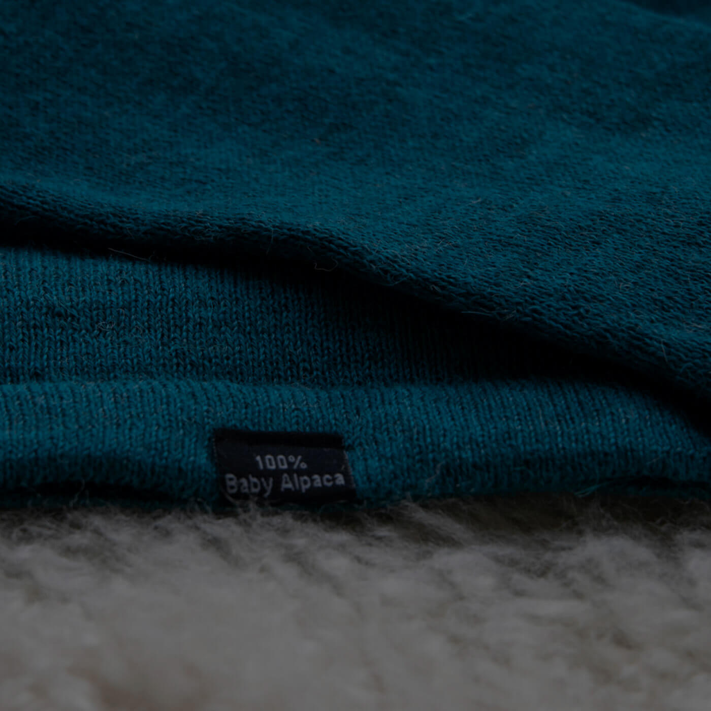 Nahaufnahme Etikett 100 Prozent Babyalpaka auf türkisfarbigem Textil