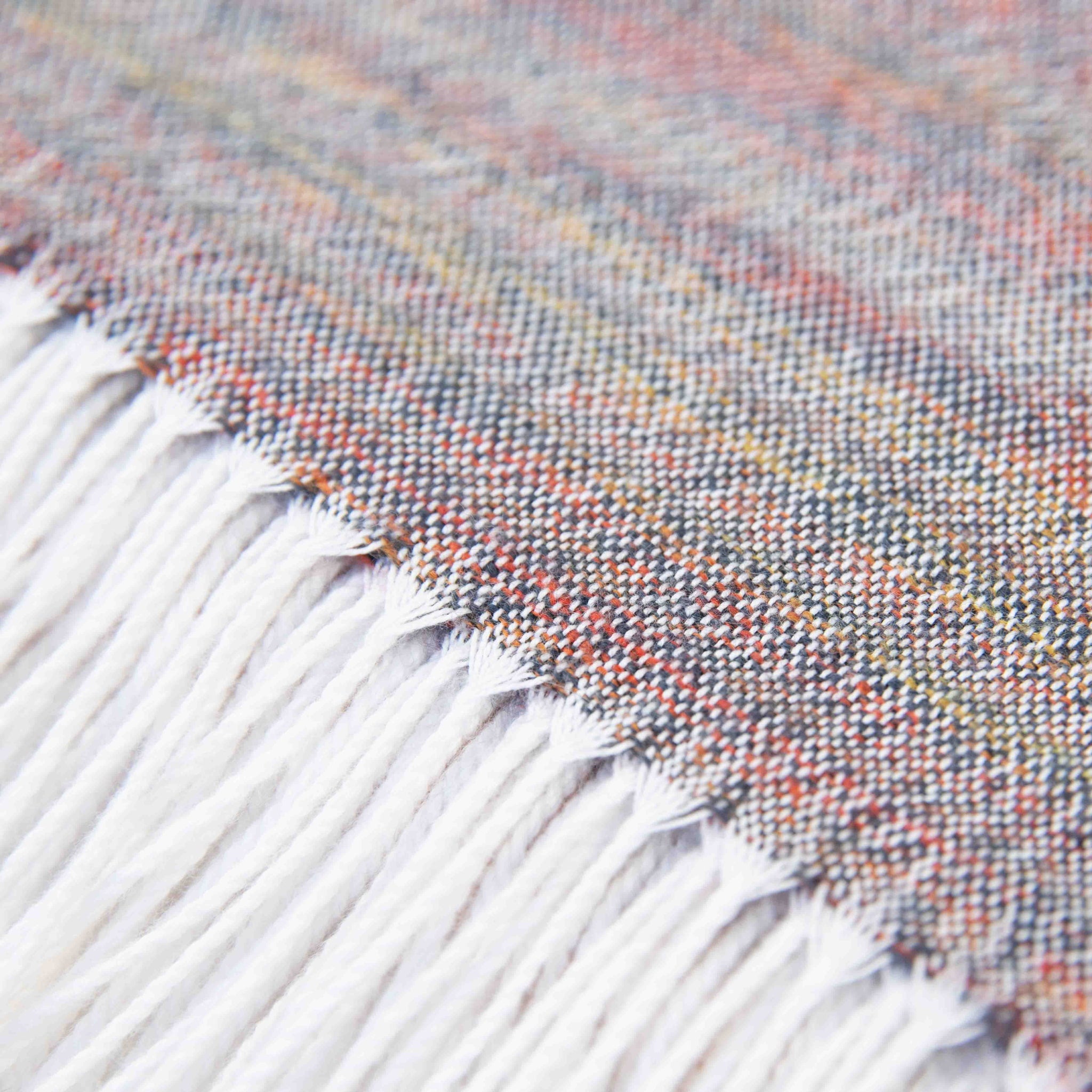 Nahaufnahme Textil und Fransensaum des Alpaka Plaids in creme zeigen die feine Verarbeitung