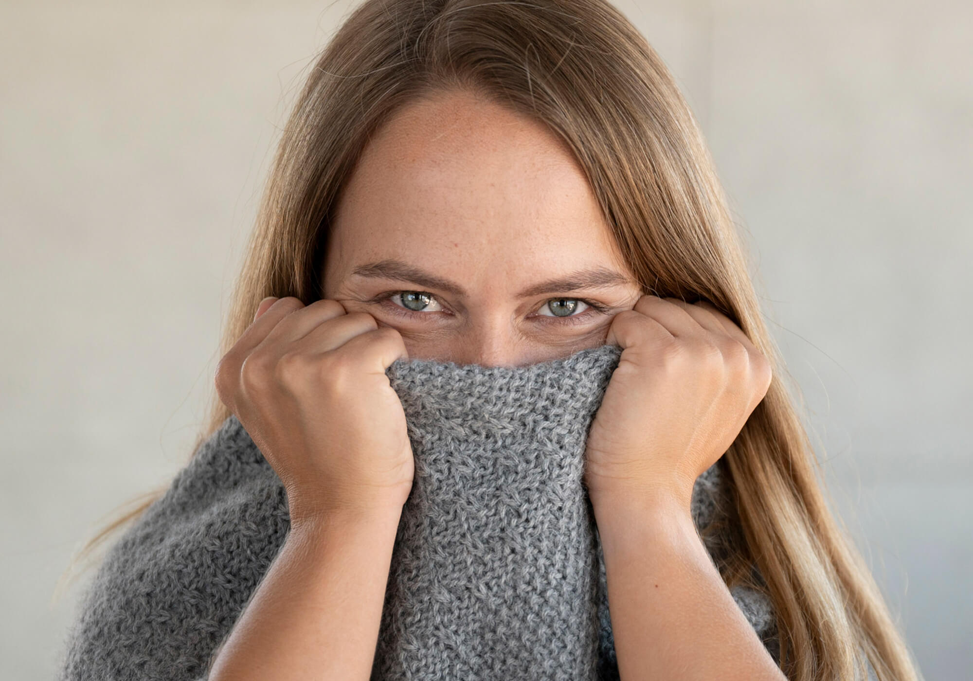 Frau kuschelt sich in ihren weichen Alpaka Strickponcho Naira aus 100% reiner Babyalpaka Wolle