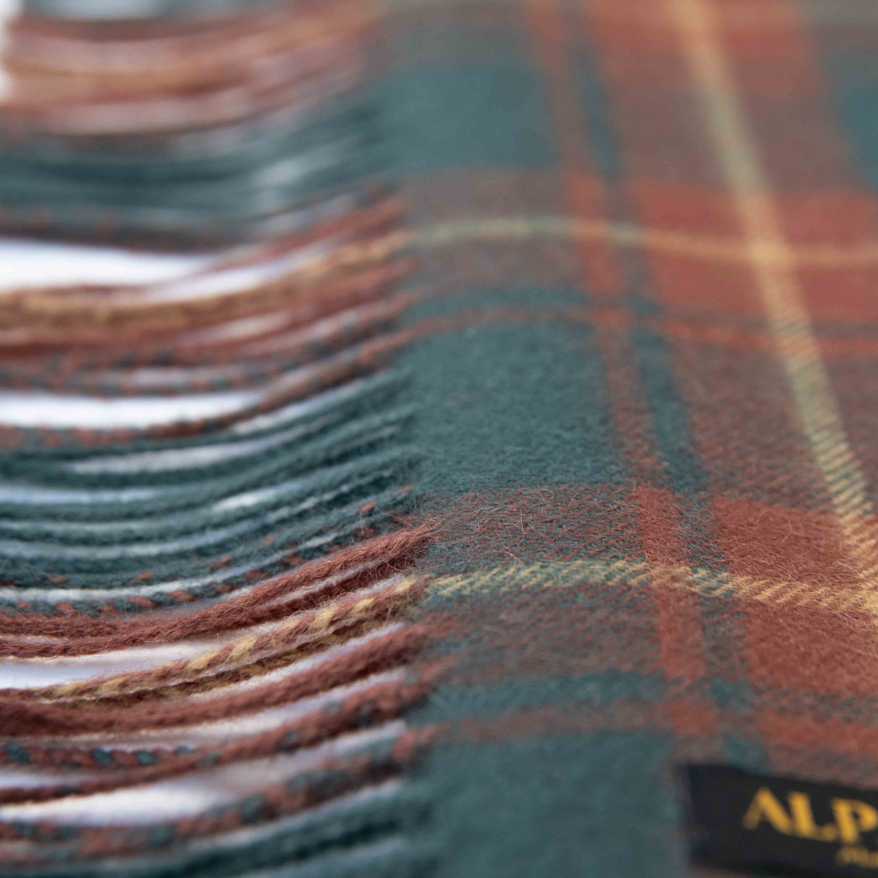 Nahaufnahme Textil und Fransen des Alpaka Schals Schottenkaro in dunkelrot von Alpakin