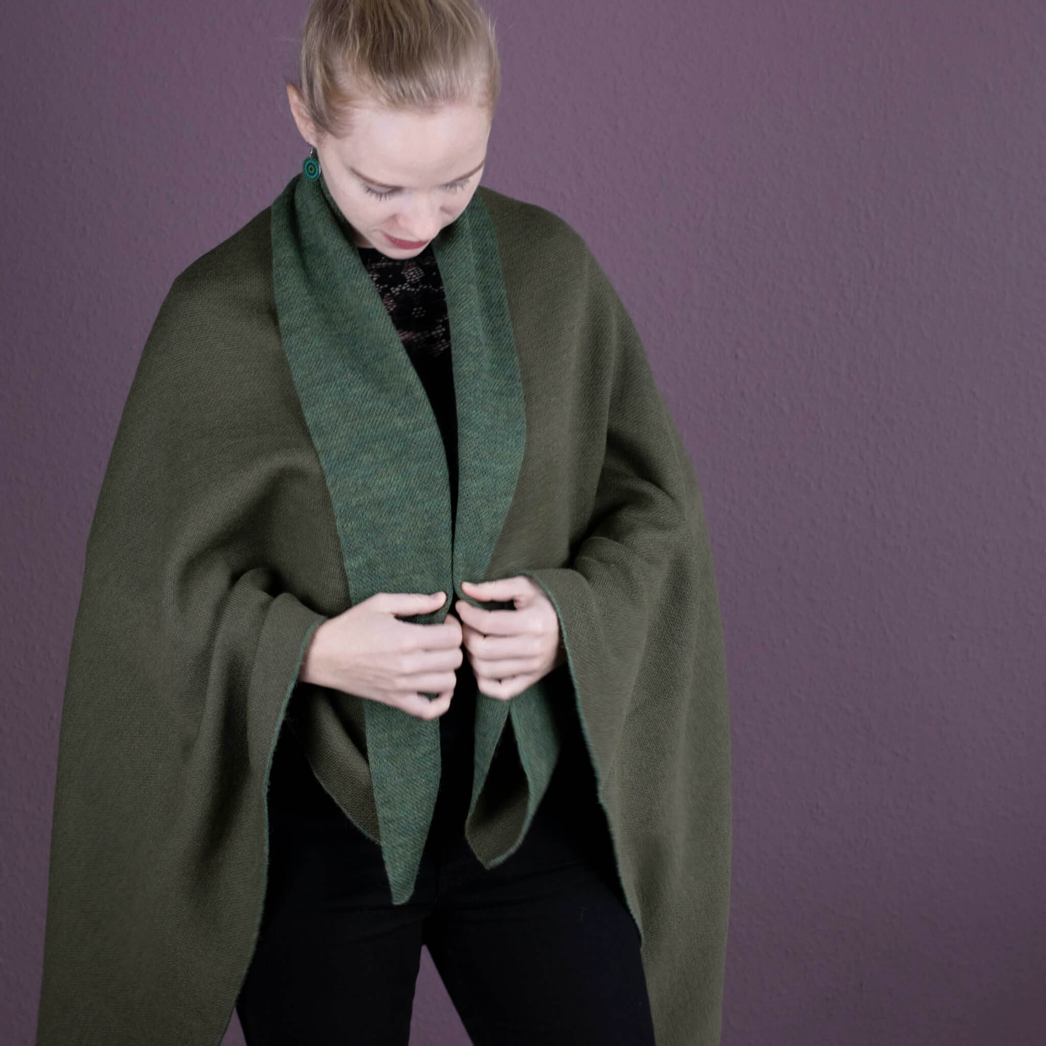 Blondes Model trägt die Iwa Alpaka Poncho Decke - dank ihres simplen Schnitts kann sie auch als Decke verwendet werden