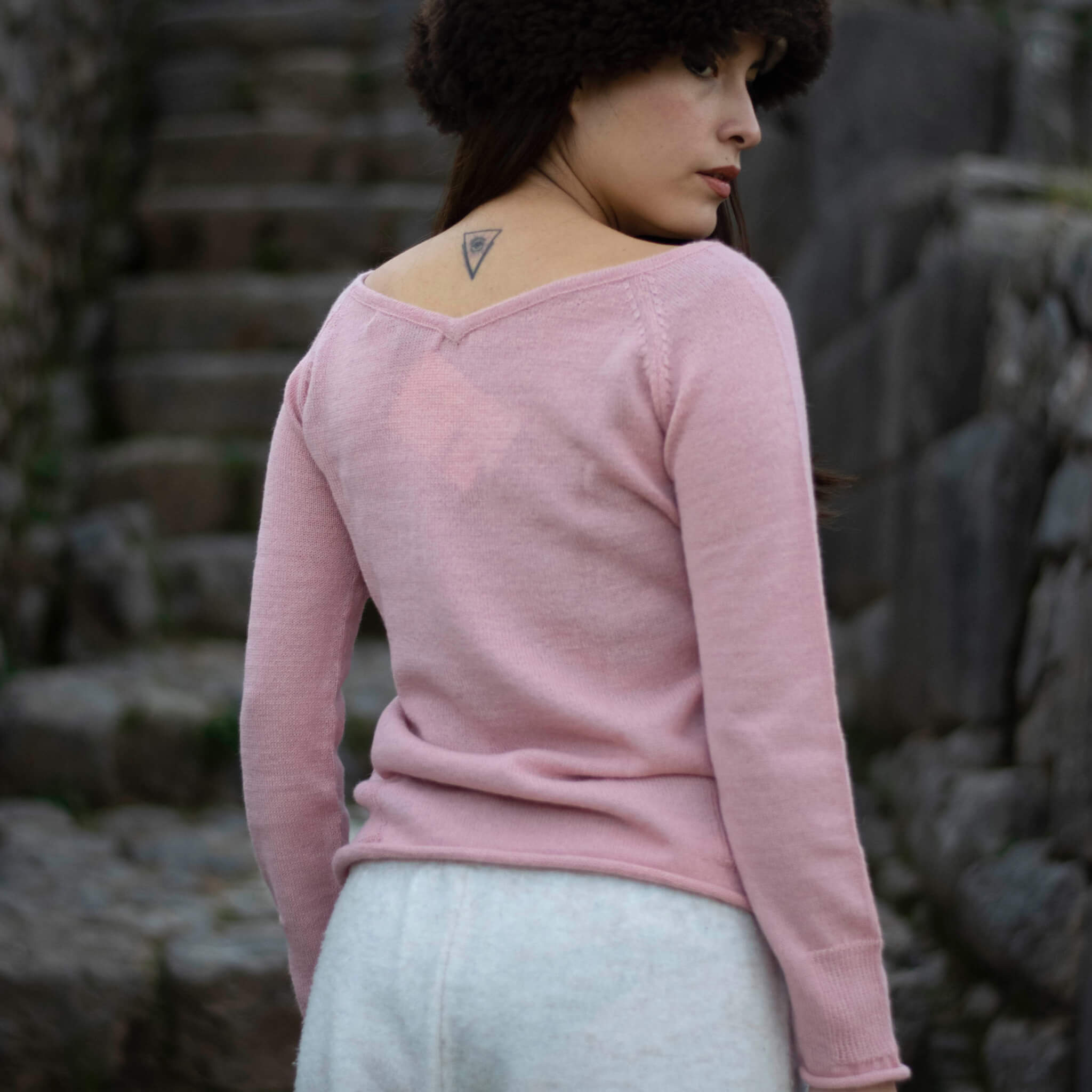 Rückansicht eines weiblichen Models, die den Mia Alpaka Pullover von Alpakin mit Auschnitt vorne und hinten in rosa trägt