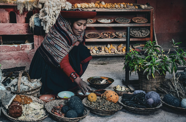 Peruanische Frau mit traditioneller Kleidung färbt Alpakawolle mit verschiedenen Pflanzen