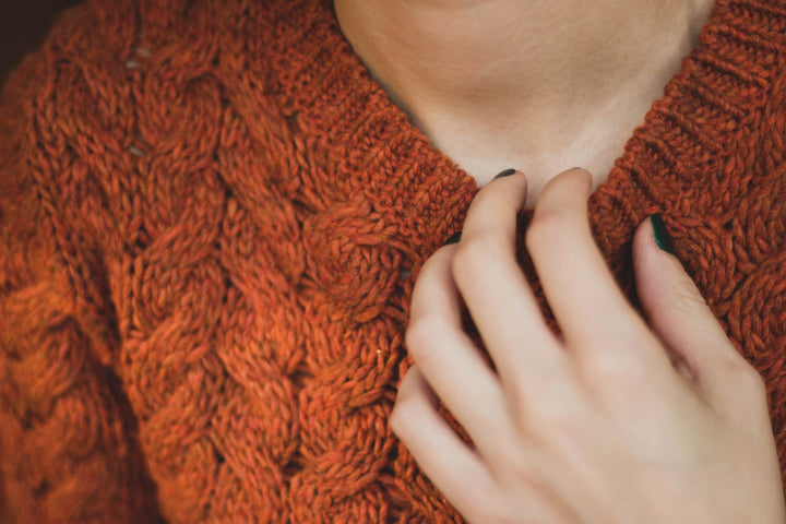 Frau mit orangenem Grobstrickpullover 