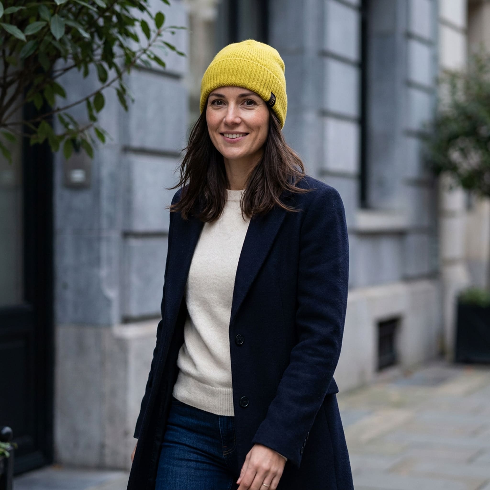 Frau kombiniert ein elegantes Outfit mit einer gelben Beanie Mütze aus reiner Alpakawolle für angenehme Wärme