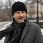 Mann mit grauem Bart trägt die Winddichte Alpaka Beanie Mütze in schwarz zu Mantel an kaltem Wintertag mit Wind