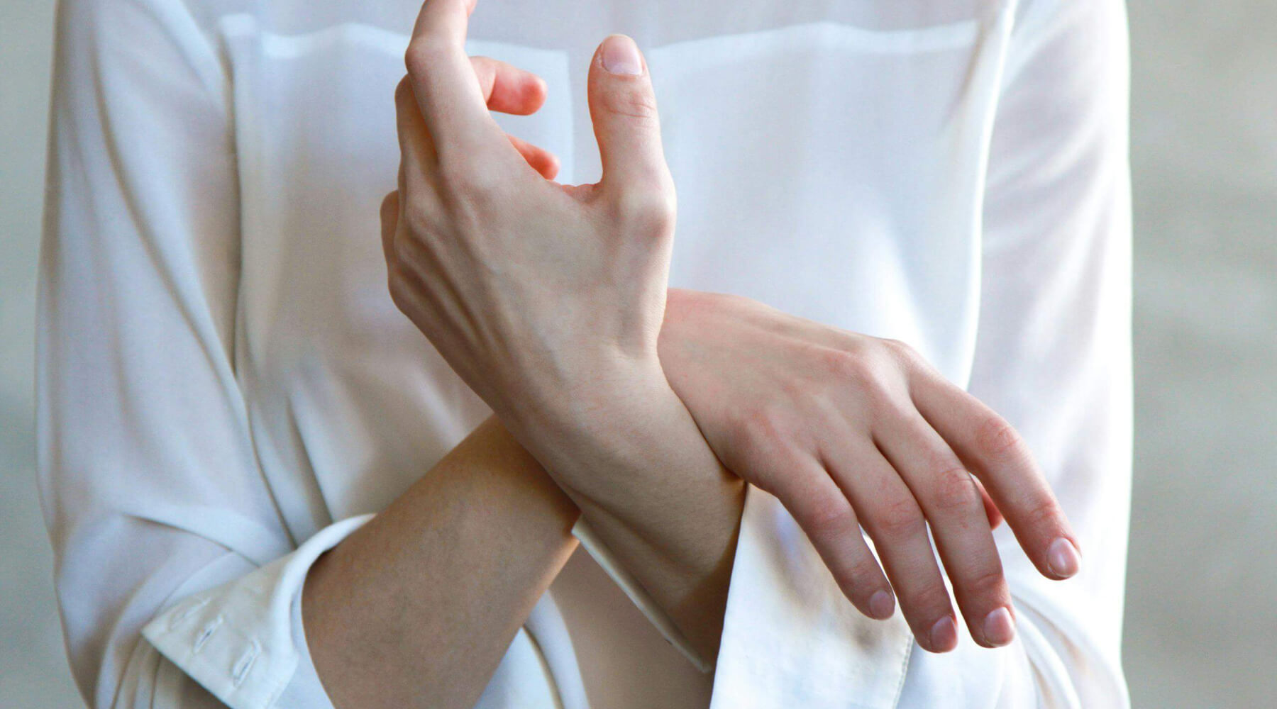 Frau mit weißer Bluse überkreuzt Hände