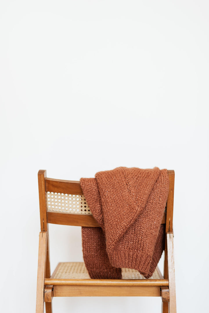Alpaka Pullover hängt über einem Stuhl und lüftet so aus