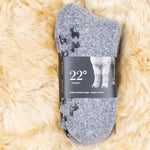 Kuschelige Alpaka Stoppersocken mit ihrer Verpackung auf Alpaka Fell platziert