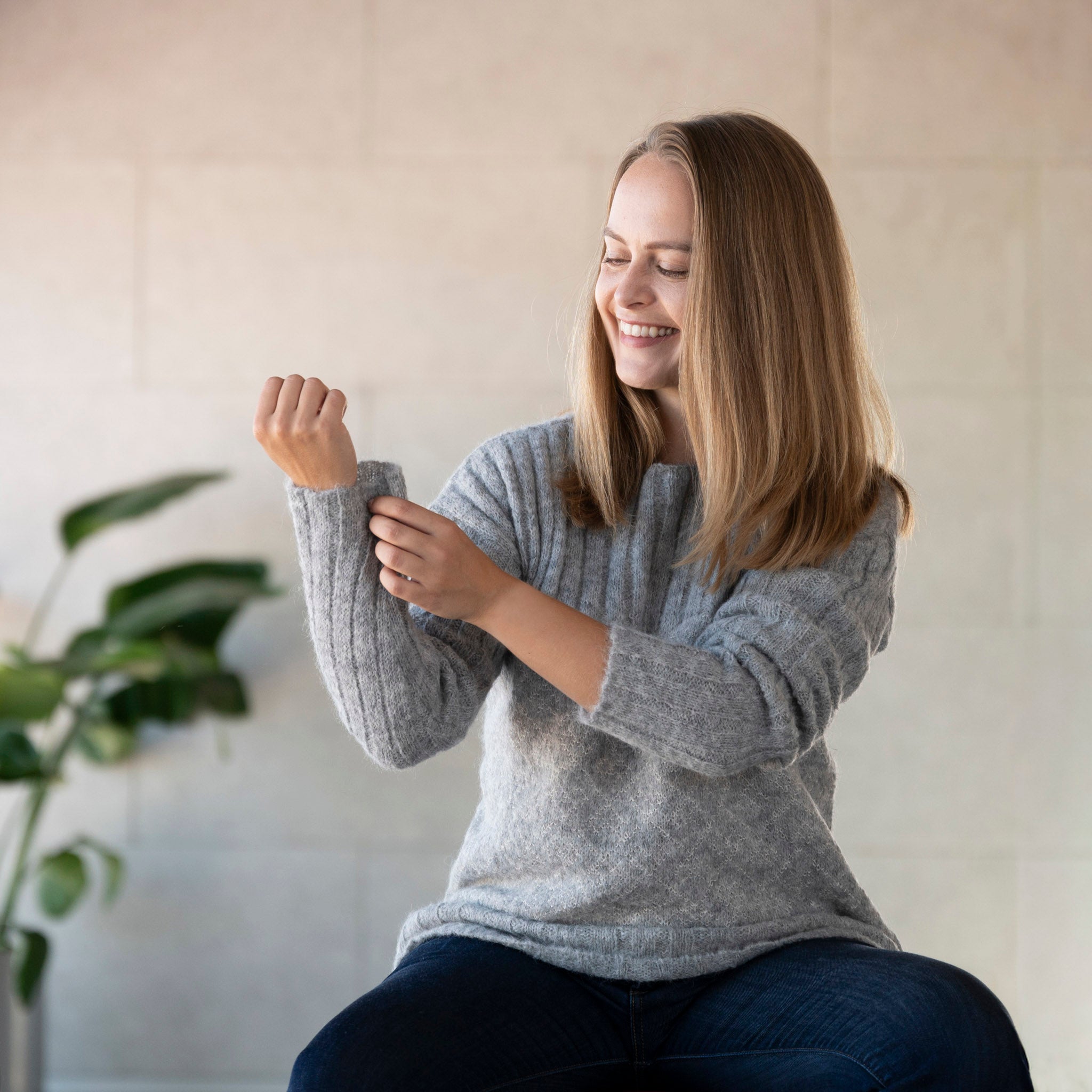 Frau mit grauem Andes Alpaka Pullover aus 100% Babyalpaka richtet ihren Ärmel