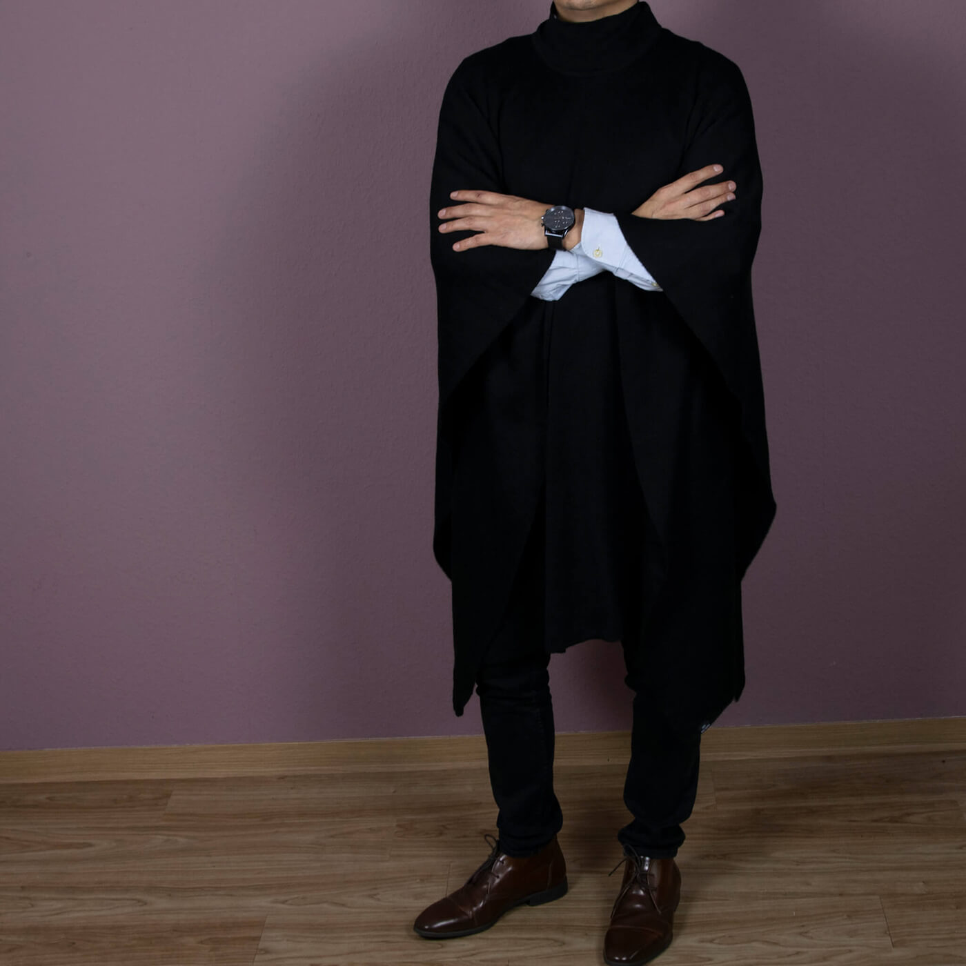 Eleganter Puma Alpaka Poncho in schwarz von Alpakin, getragen von einem Mann, der die Arme verschränkt