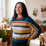 Dunkelhaarige Frau in ihrem Atelier trägt den farbenfrohen Cusi Alpaka Pullover - ideal für den Frühling
