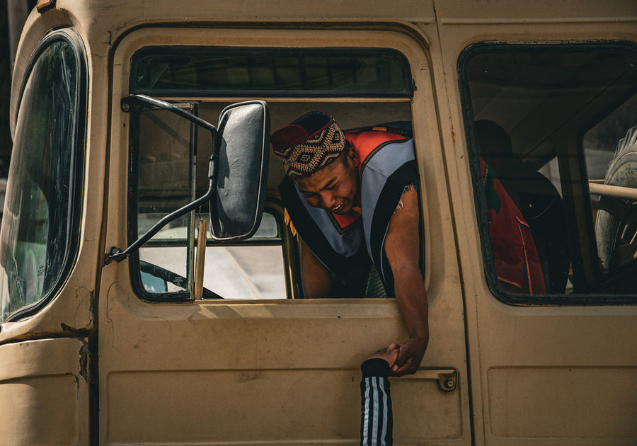 Peruanische Frau mit typisch-farbiger Kleidung gibt jemand aus altem Bus heraus die Hand