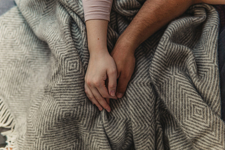Zwei Hände halten einander auf einer Alpaka Decke mit Muster