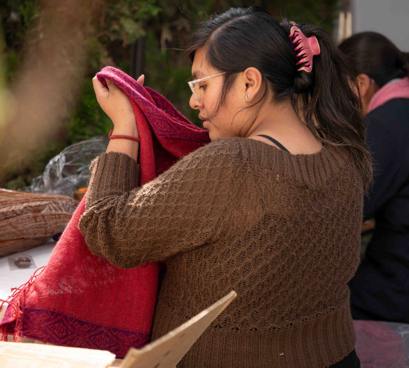Peruanische Schneiderin mit Alpaka Poncho FLOR von Alpakin in den Händen