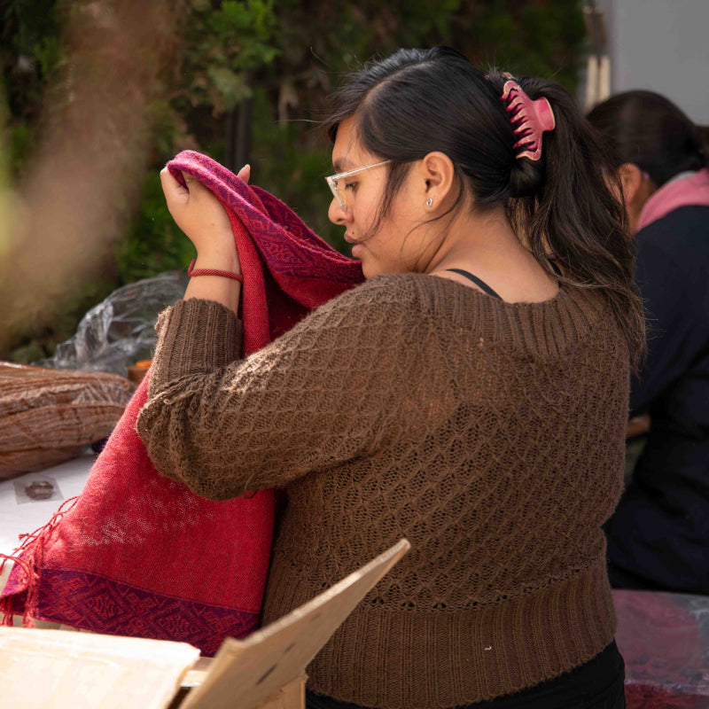 Peruanische Schneiderin mit Alpaka Poncho FLOR von Alpakin in den Händen