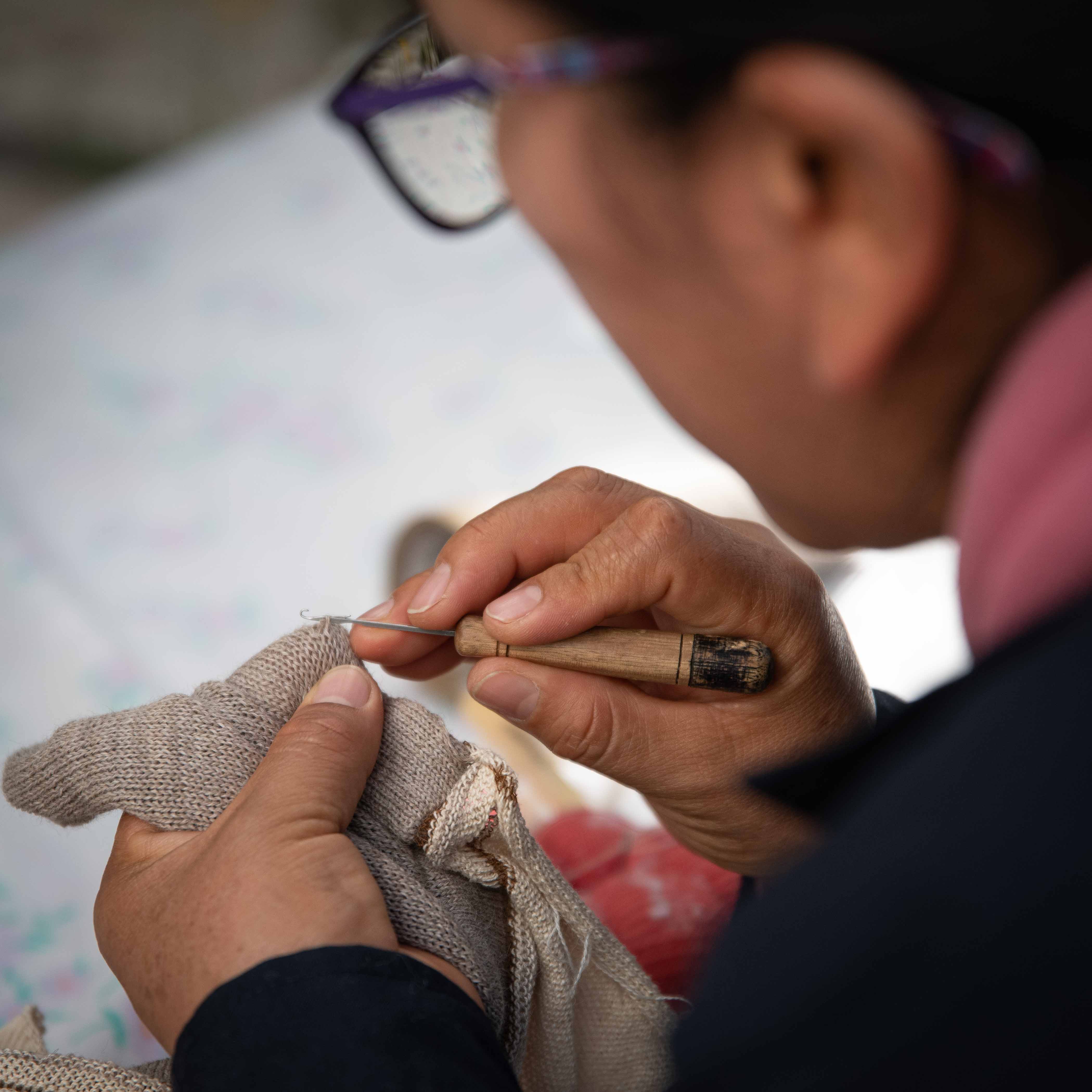 Handarbeit Fertigung Alpaka Kleidung peruanische Frau mit Brille näht