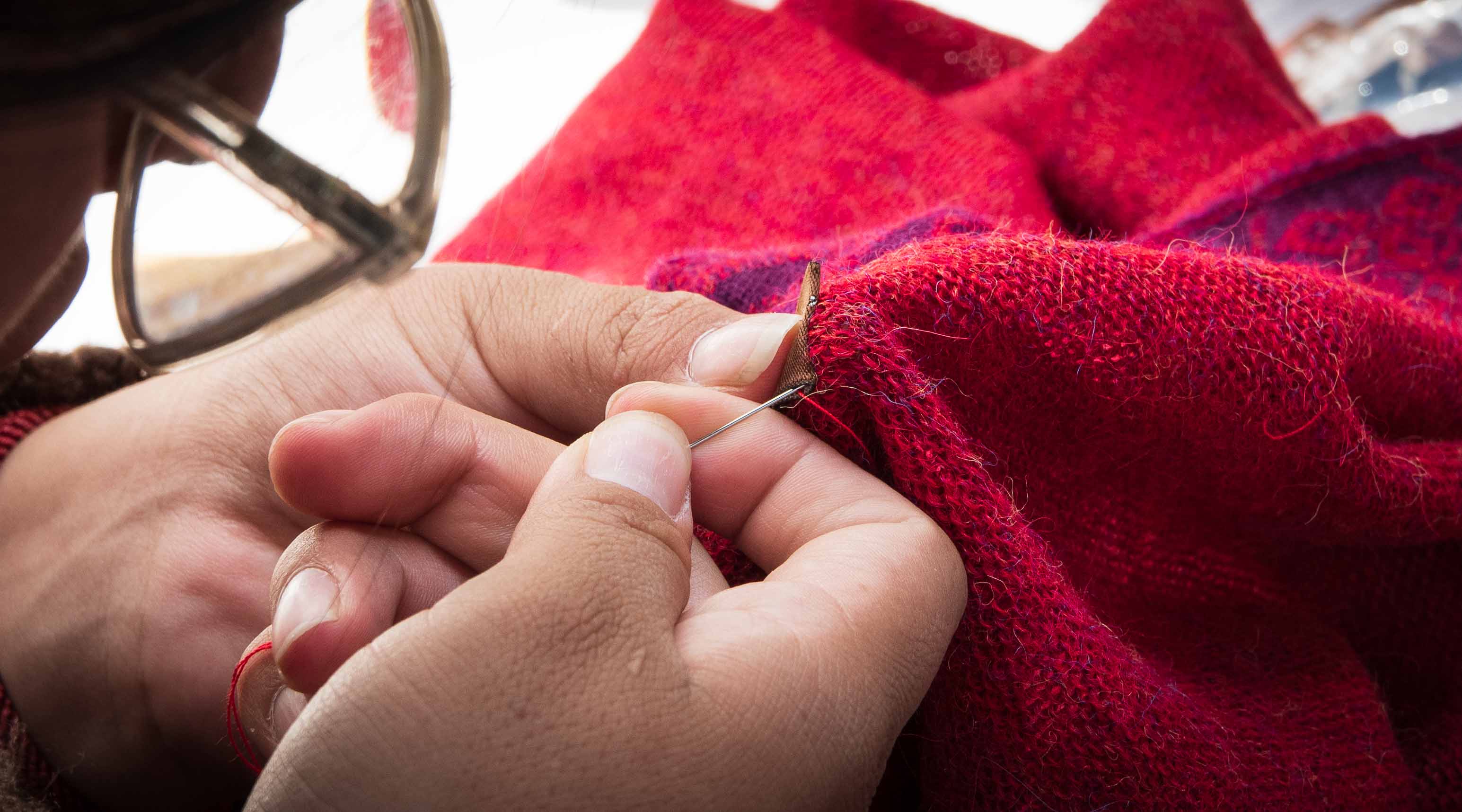 Handarbeit rotes Textil bei der Fertigung von Alpaka Kleidung für Alpakin