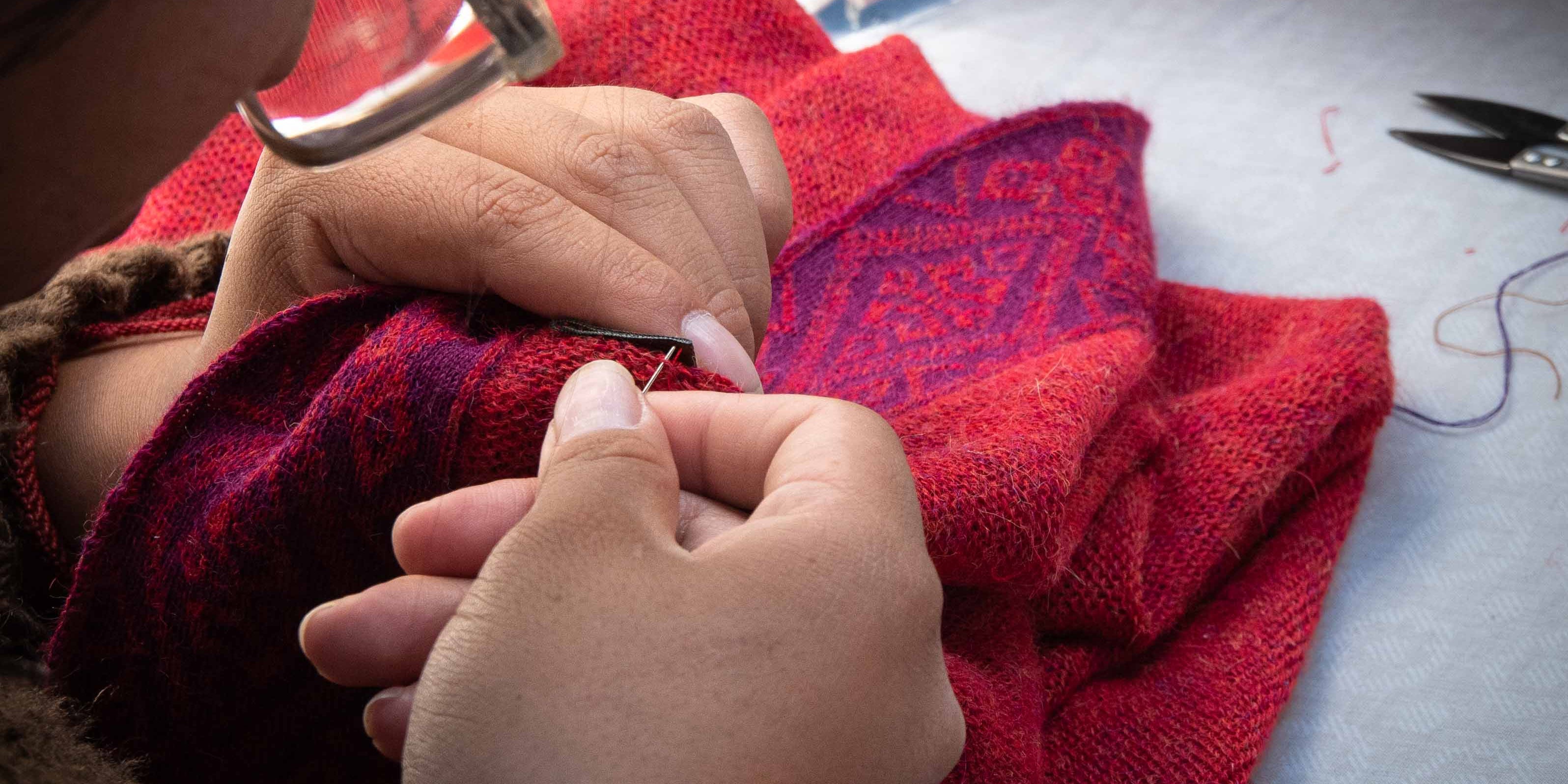 Peruanische Frau näht von Hand Etikett in Alpaka Poncho FLOR