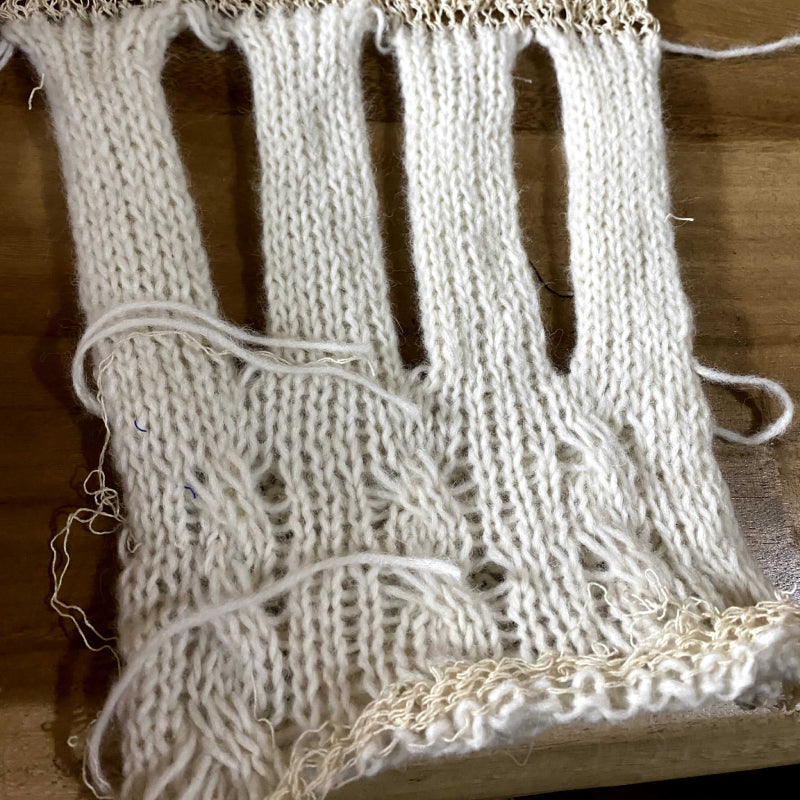 Weißer Handschuh aus Alpakawolle in der Fertigung als erster Entwurf