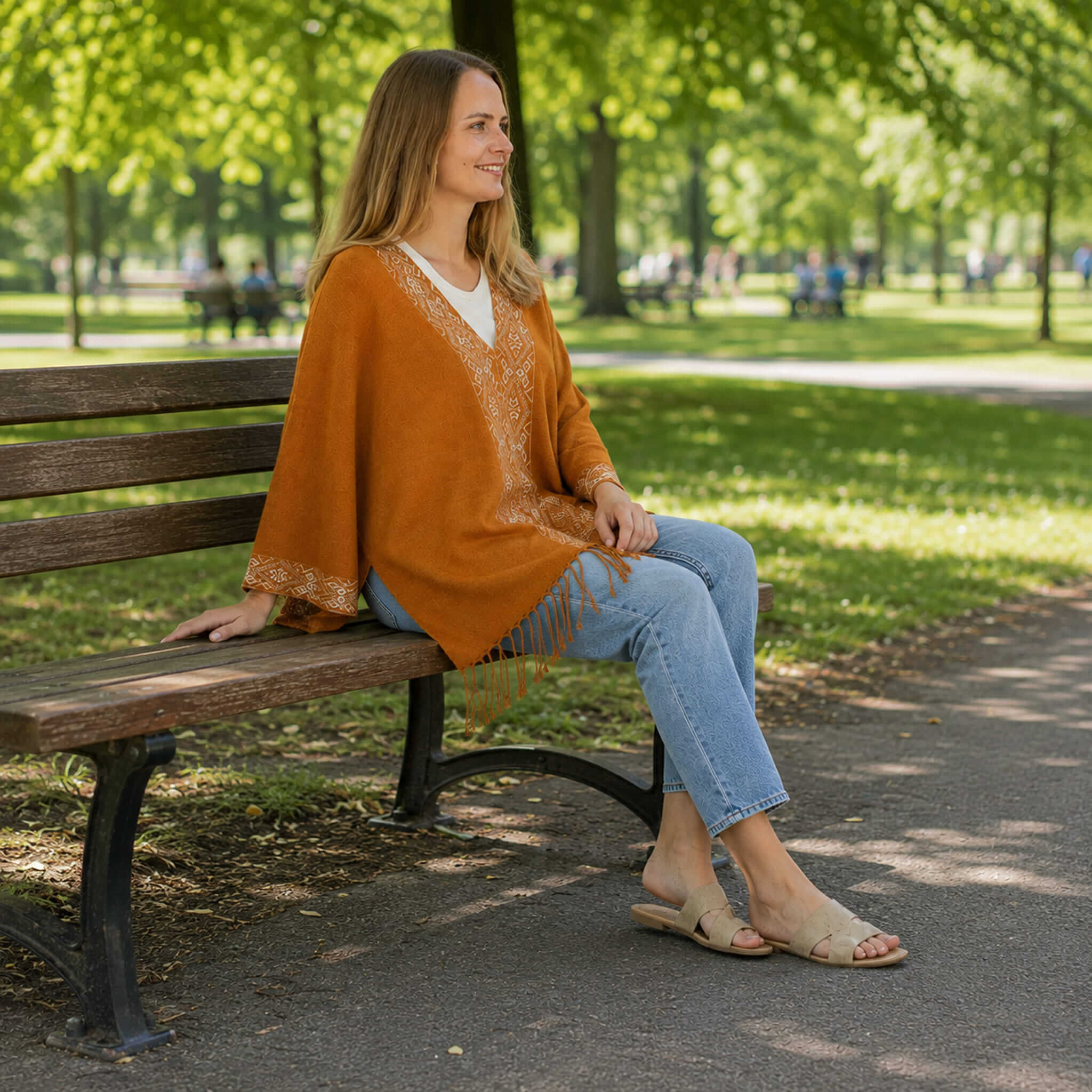 Frau sitzt mit ihrem Flor Sommerponcho auf einer Parkbank