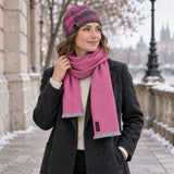 Frau trägt vor einer Stadtkulisse im Winter das Premium Set in pink, bestehend aus feinem Babyalpaka Schal und Merino Mütze mit Maulbeerseide für angenehme Wärme
