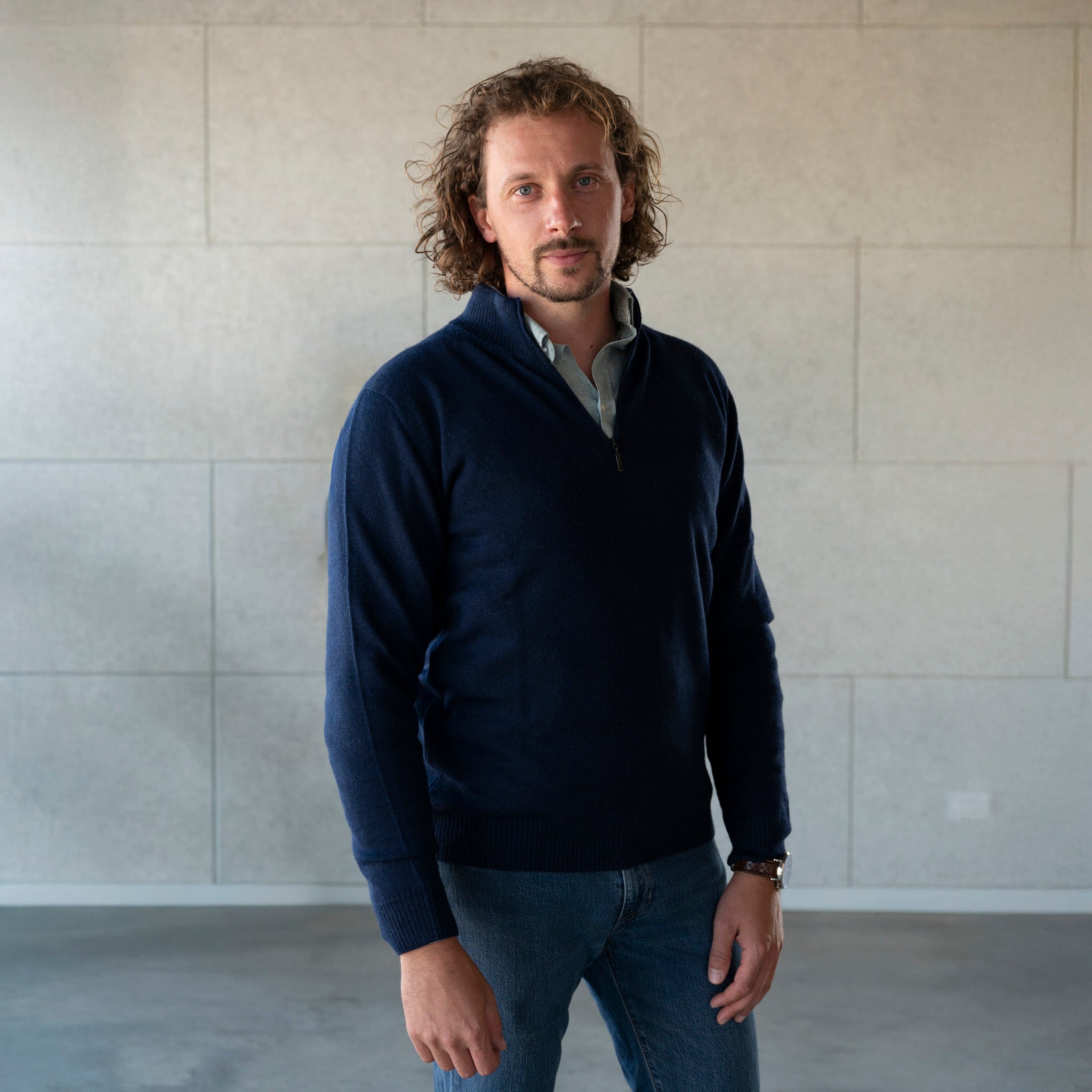 Weicher Alpaka Troyer für Herren in elegantem dunkelblau, getragen von männlichem Model mit Locken