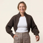 Attraktive Frau trägt die Killa Strickjacke aus Alpakawolle in Alpaka Naturfarbe und lächelt glücklich in die Kamera