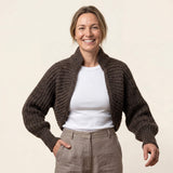 Attraktive Frau trägt die Killa Strickjacke aus Alpakawolle in Alpaka Naturfarbe und lächelt glücklich in die Kamera