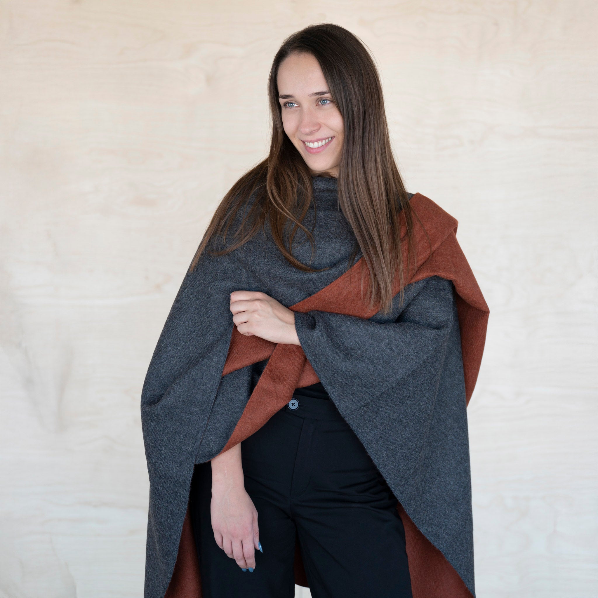 Dunkelhaariges Model trägt den Koya Alpaka Poncho Umhang in Farbe Holzkohle und Pfirsich