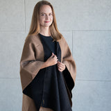 Blonde Frau trägt den Koya Alpaka Poncho Umhang in hellbraun und schwarz