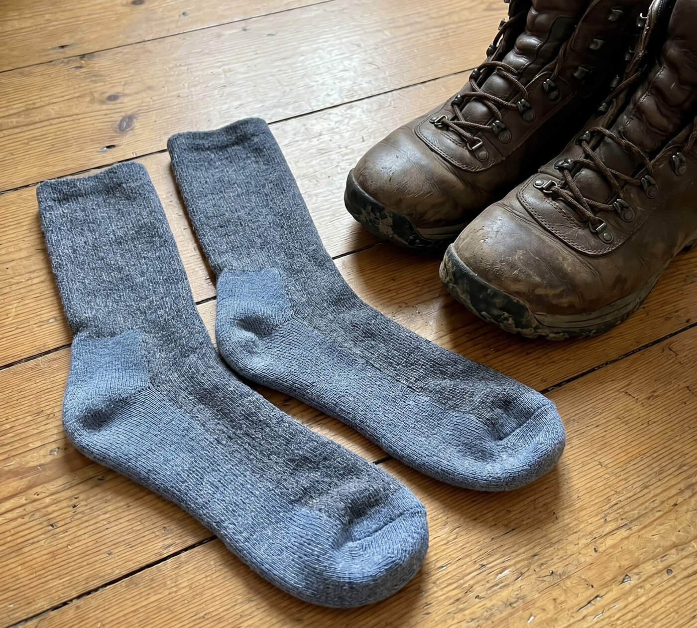 Alpaka Wandersocken neben Wanderschuhen auf einem Holzboden