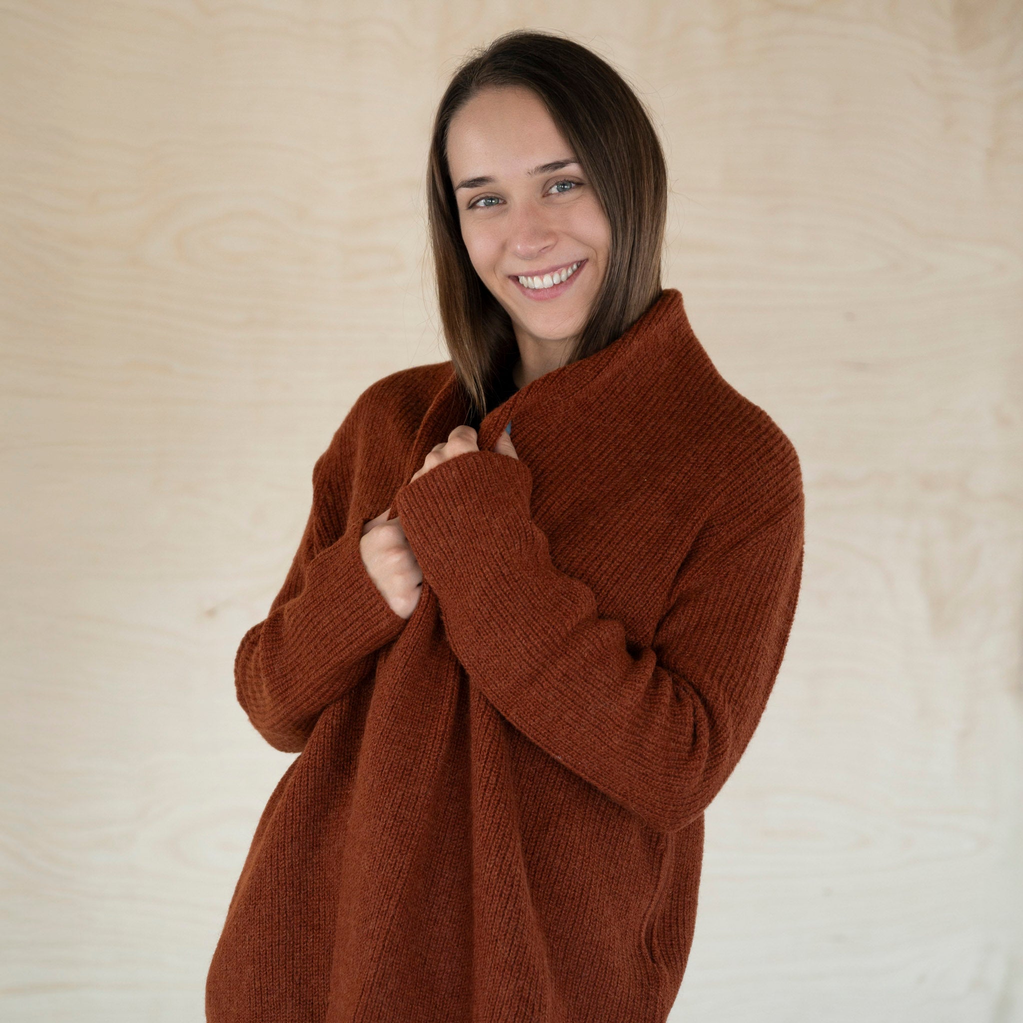 Dunkelhaarige Frau trägt den Mira Alpaka Cardigan in dunkelorange