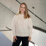 Frau trägt den Liya Alpaka Pullover von Alpakin in creme und blickt lächelnd in die Kamera