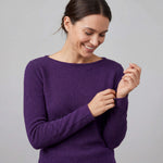 Frau fühlt die Weichheit ihres 100% reinen Babyalpaka Pullovers und lächelt dabei glücklich