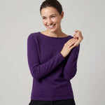 Frau blickt lachend in die Kamera und trägt den Luna Alpaka Pullover in dunkellila