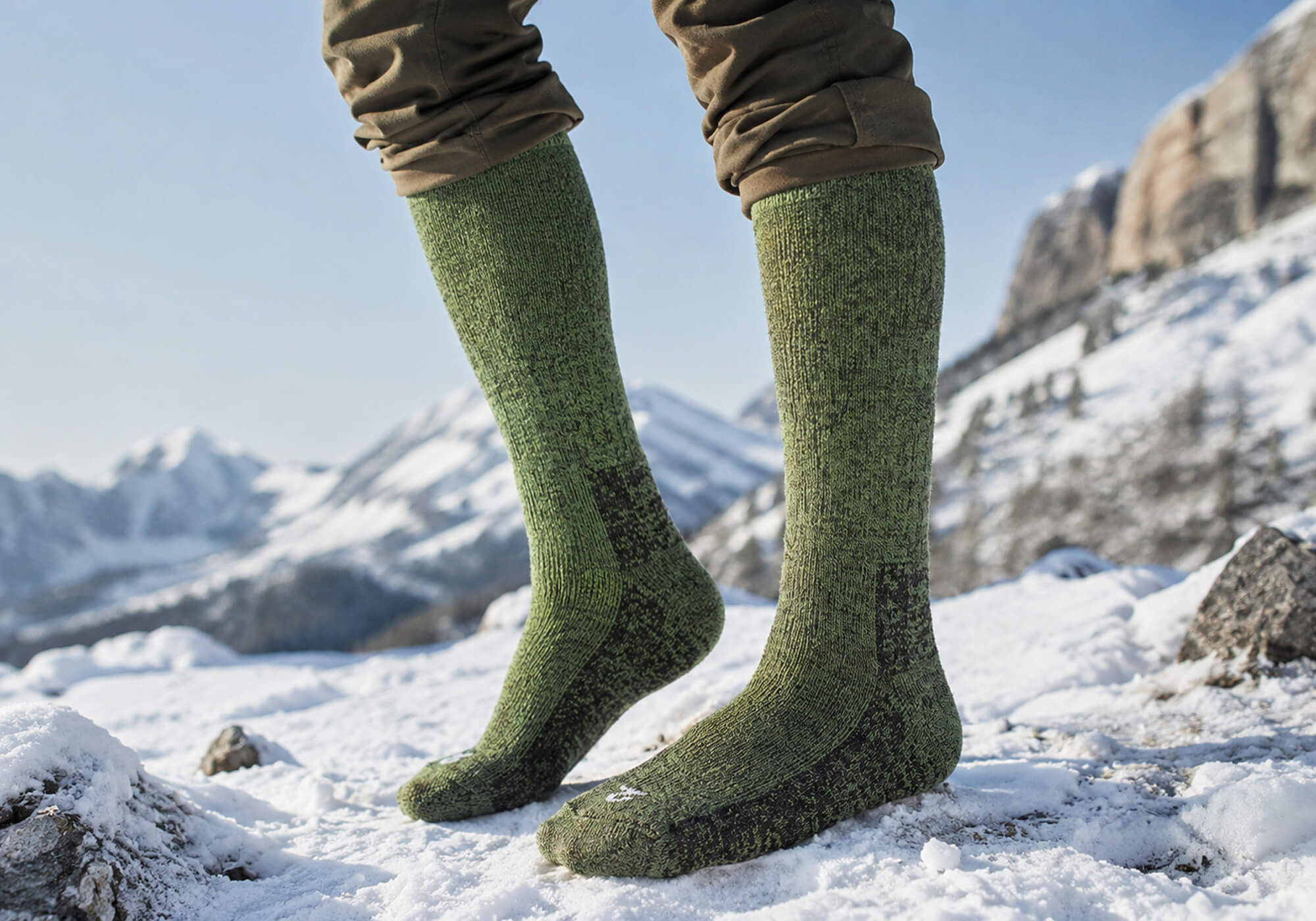 Kniehohe Alpaka Thermo Strümpfe in grün getragen in Schneelandschaft gegen kalte Füße