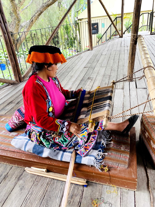 Peruanerin in typischer Kleidung webt nach alter Tradition mit Alpakawolle