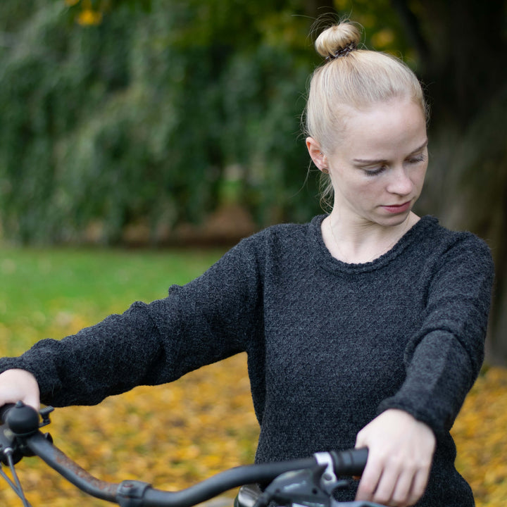 Alpaka Pullover Sisa für Damen in schwarz getragen von blondem Model auf Fahrrad im Freien