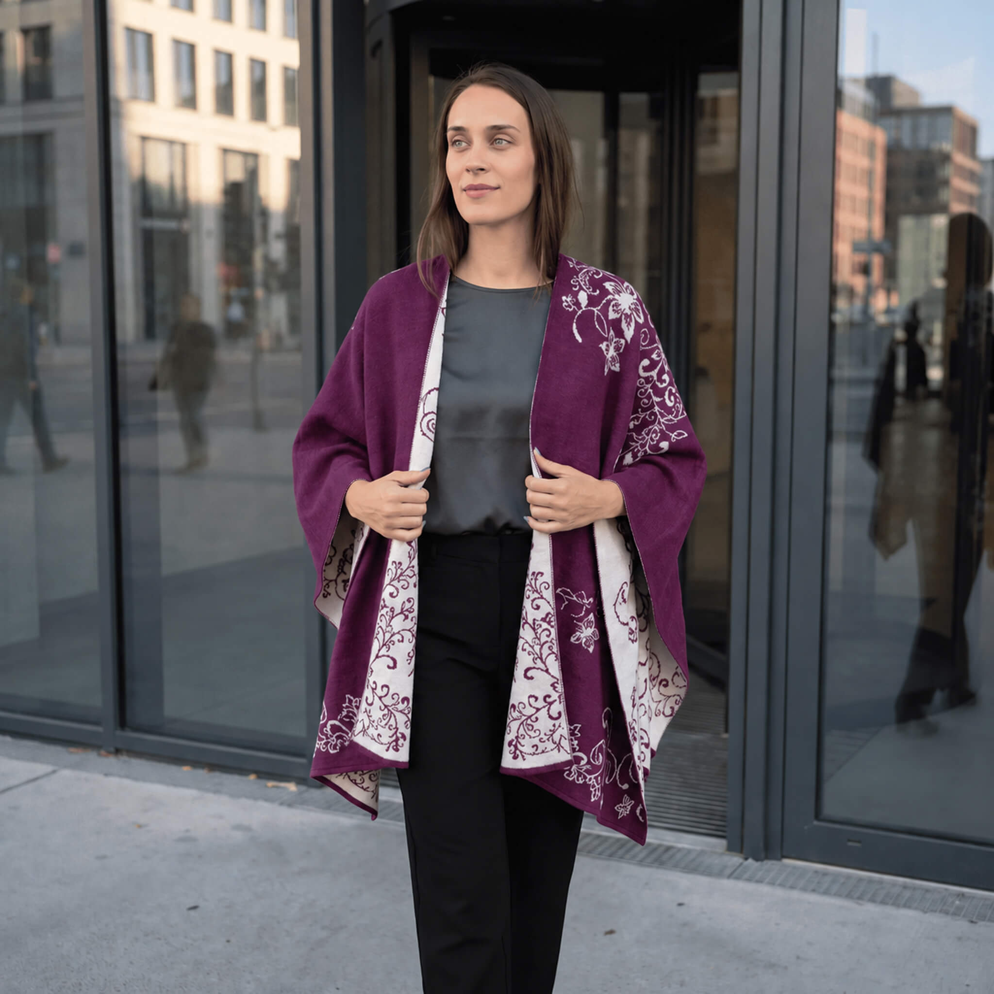 Frau aus dem Büro trägt selbstbewusst ihren Alpaka Poncho mit Blumenmuster