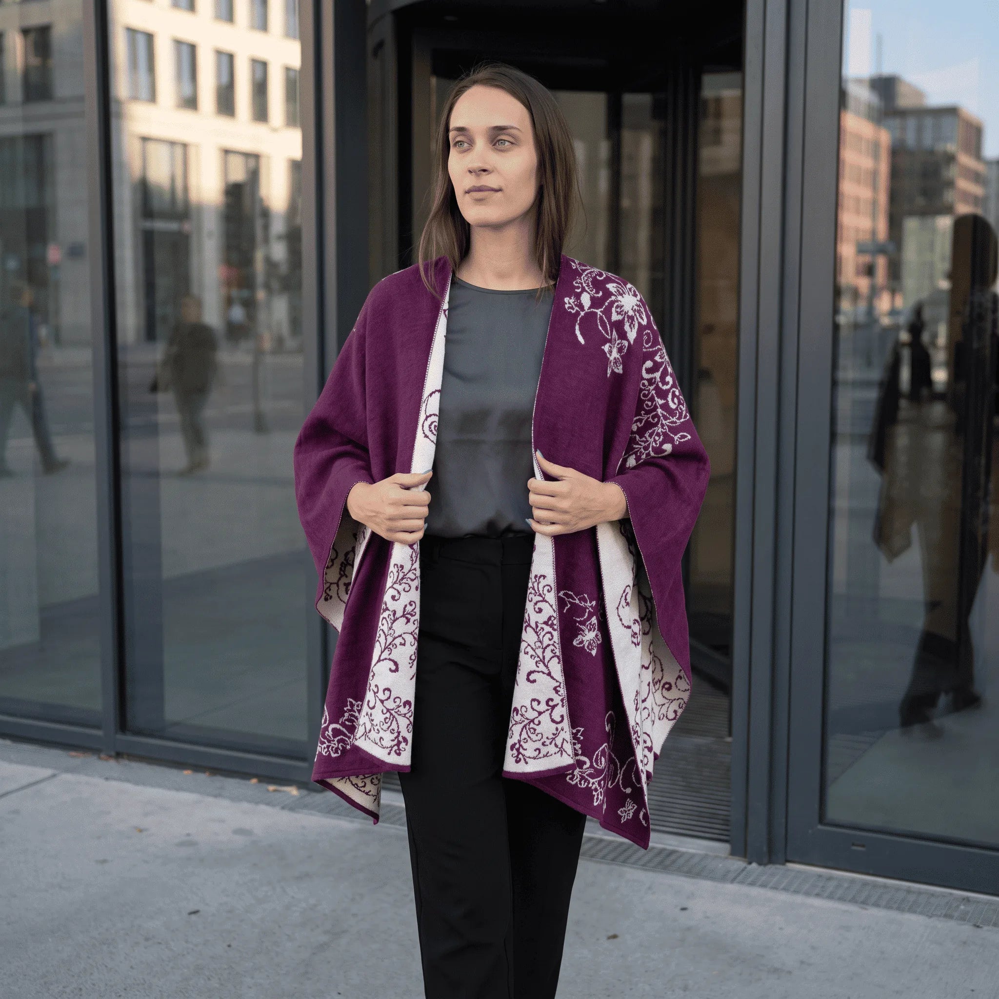 Frau aus dem Büro trägt selbstbewusst ihren Alpaka Poncho mit Blumenmuster