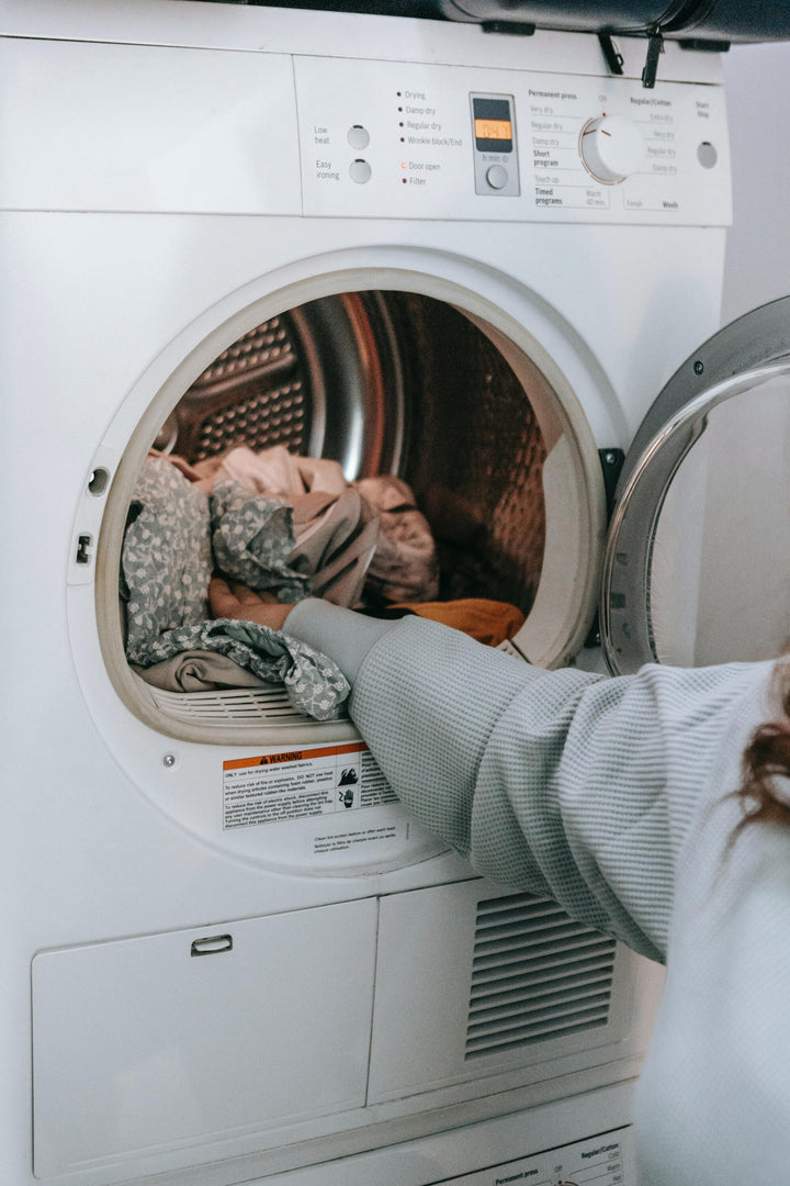 Frau legt Kleidung in Waschmaschine