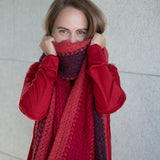 Blonde Frau bedeckt mit ihrem kuschelweichem Babyalpaka Schal in rot ihr Gesicht