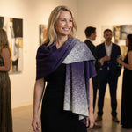 Blonde Frau trägt auf einer Abendveranstaltung den eleganten Poncho Yana aus Alpakawolle in dunkellila