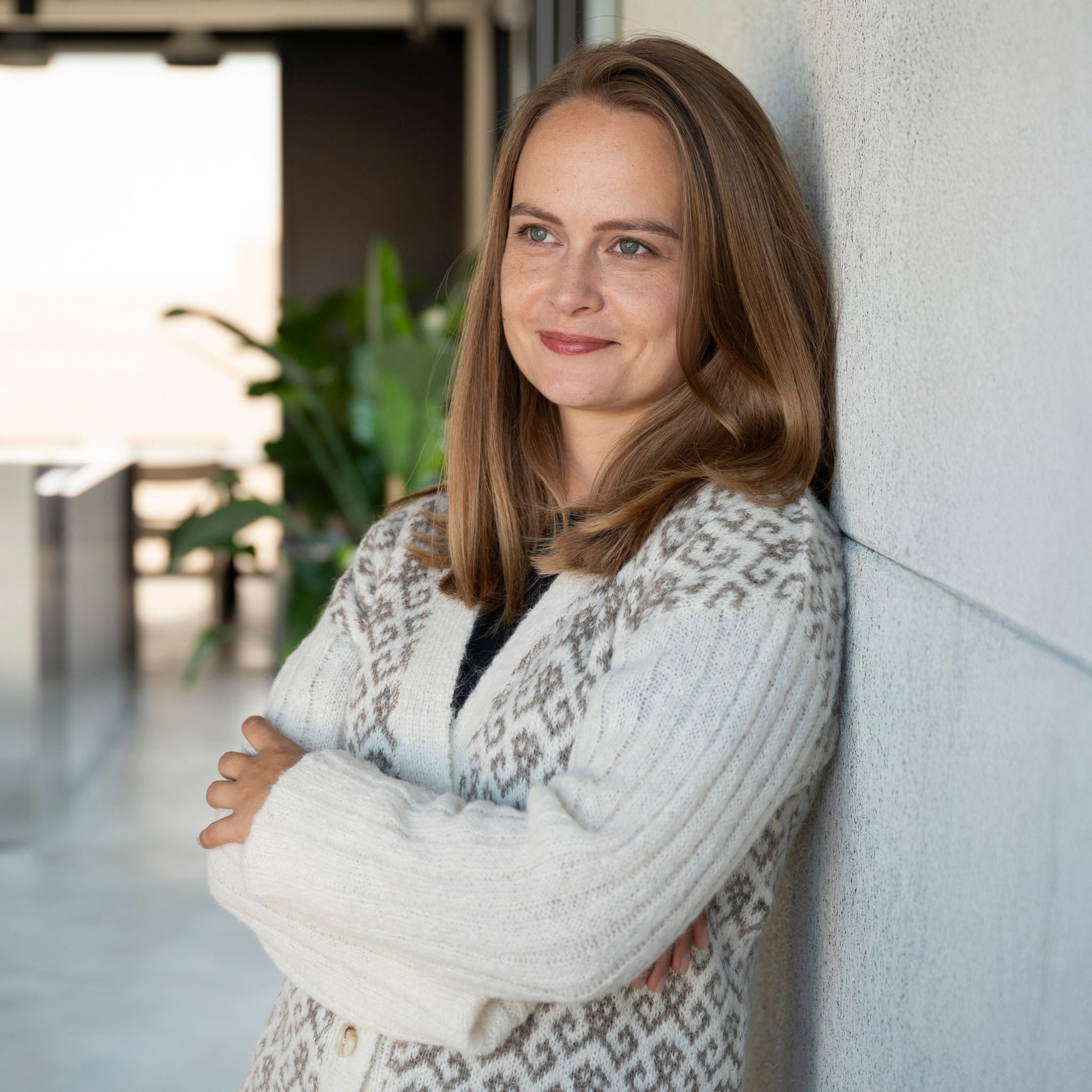 Weißer Yurac Alpaka Strickmantel von Alpakin, getragen von Model mit verschränkten Armen